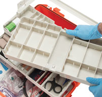 close up of a man in blue medical gloves pulling out the Customisable Pullout Trays on an orange peli air 1465ems case
