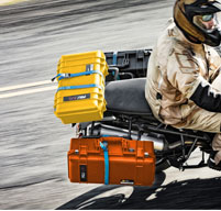 a man on a motorbike carrying peli air cases on the back