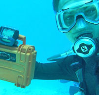 Scuba diver holding a yellow explorer case under water to show it is watertight