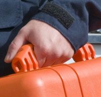 close up of a man holding the rubber over-molded handle of an orange peli 1460em case
